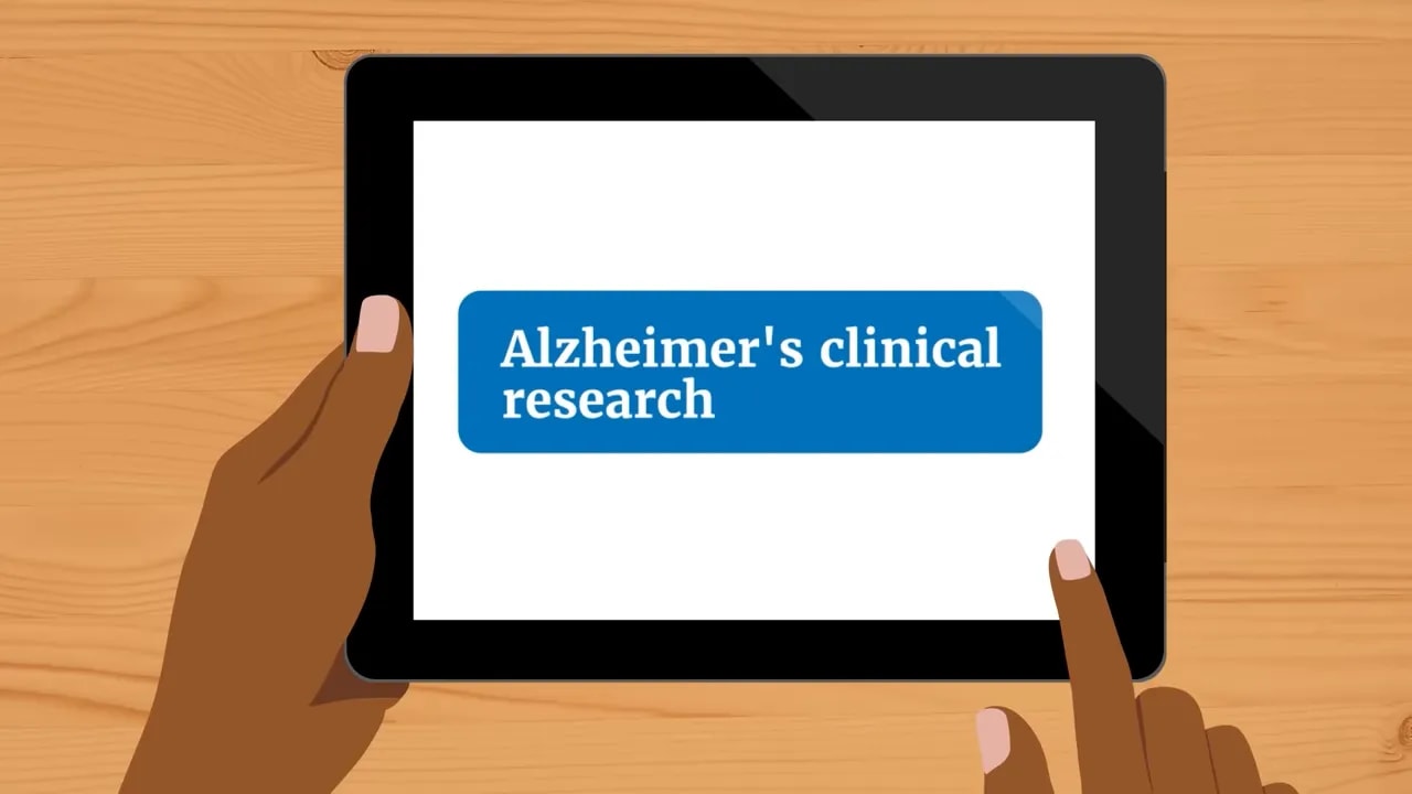 Hands holding a tablet displaying the words Alzheimer’s clinical research