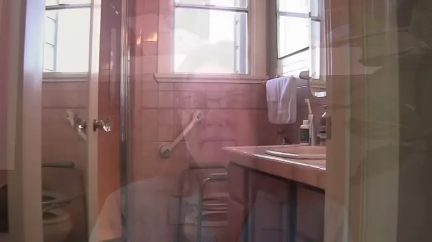 Bathroom with shower area sink grab bar and bath chair visible