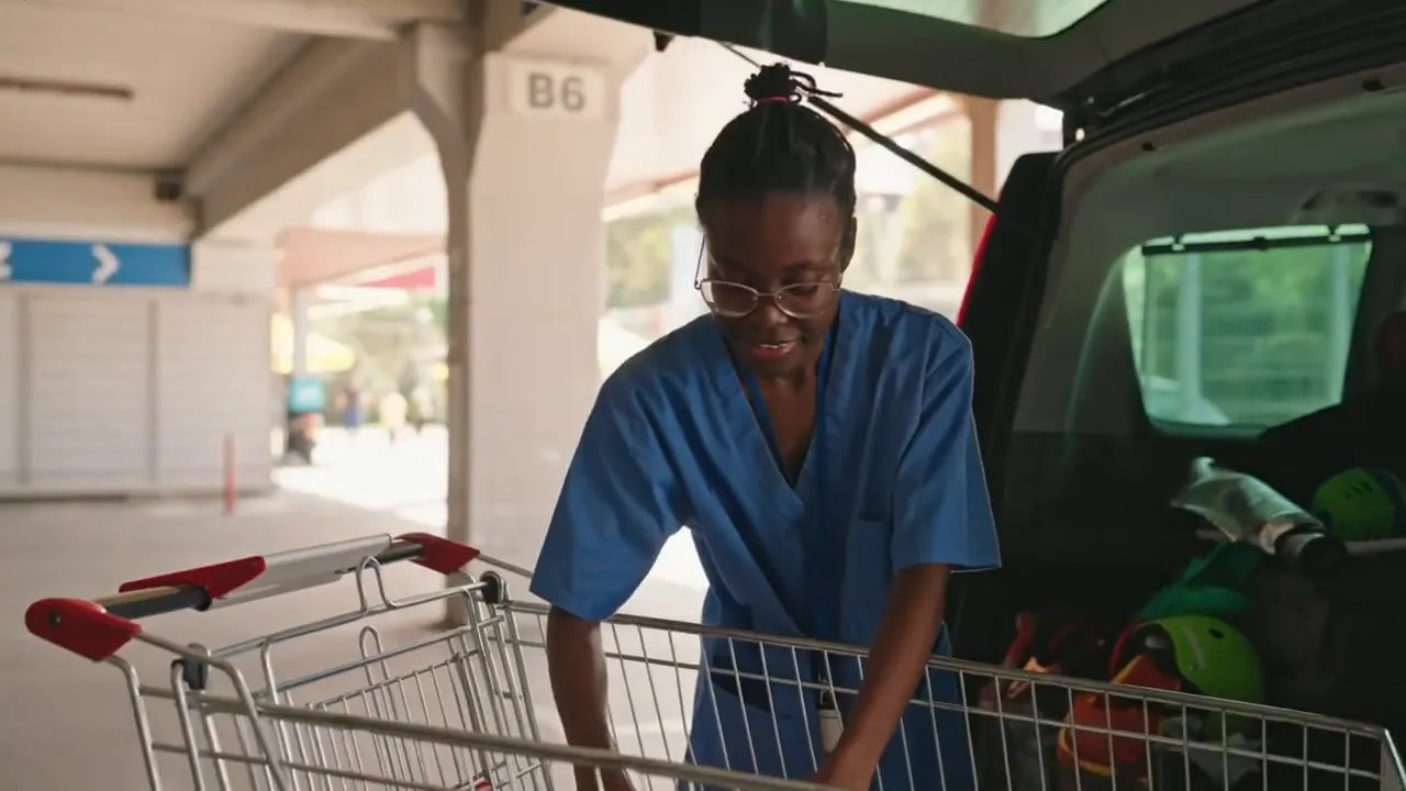 Caregiver loading groceries into the back of a vehicle in a parking area