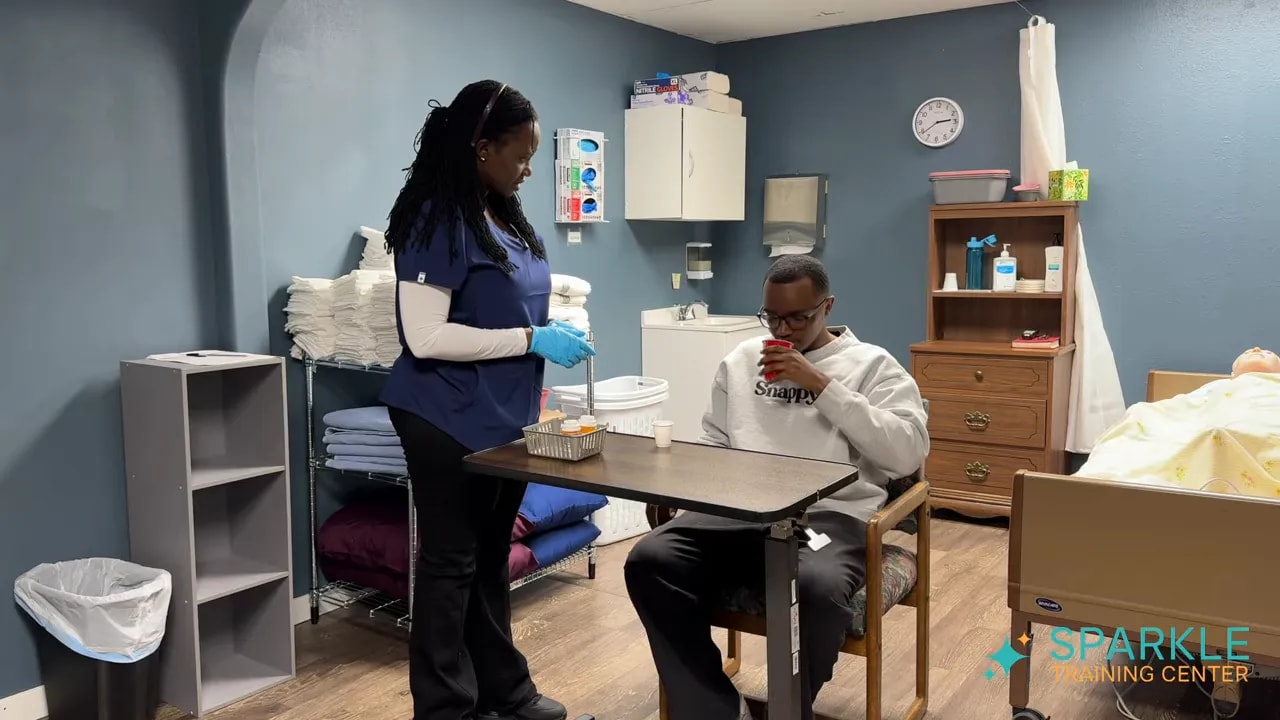 client drinking from red cup while caregiver stands beside the table observing